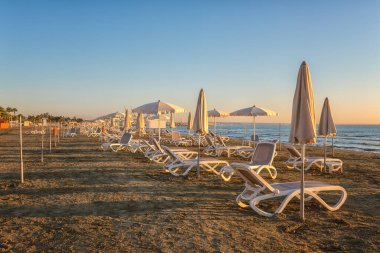 Gündoğumunda Larnaka kumsalının manzarası, Kıbrıs, turizm beldesi. Sahilde şemsiyeler, dinlenme yerleri, seyahat geçmişi, yaz tatilleri konsepti...