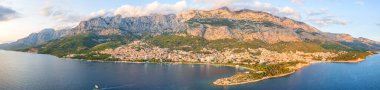 Hırvatistan 'ın Dalmaçya kentinin Makarska kentinin hava manzarası. Yatı, denizi, mimarisi ve kayaları olan yaz manzarası, Adriyatik sahil kıyısındaki ünlü turizm beldesi, seyahat arka planı, geniş panorama