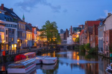 Belçika 'nın tarihi şehir merkezi Gent' in (Gent) manzarası. Ortaçağ mimarisi ile güzel şehir manzarası, anıtsal simgeler ve turist botları ile Lys nehri, dış seyahat arka planı