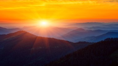 Amazing mountain landscape at sunrise, scenic view of silhouettes of the Carpathian mountains range, fantastic colorful sky with clouds and rising sun, outdoor travel background suitable for wallpaper clipart