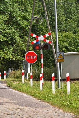 railway crossing on a forest road, the sign says not to touch the electric traction