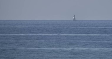 Ufukta bir yelkenli yelkenli var.