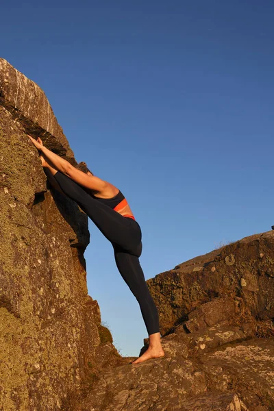 Вертикальный Снимок Зрелой Женщины Делающей Растяжку Скале Золотом Свете Восхода — стоковое фото