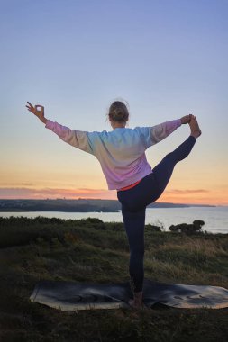Kadın denizin önünde yoga yapıyor. Uluslararası yoga günü konsepti.