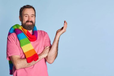 Gururlu ve yakışıklı bir adam. LGBT Gökkuşağı eşarbı omuzda, izole bir arkaplanda..