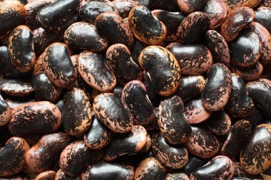 Yukarıdan bir yığın çiğ pembe, kahverengi benekli fasulye ile bej görünüyor. Yakın çekim.