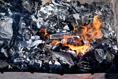 Ahşap bir haç, siyah küllere karşı ateşle yanıyor.