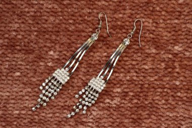 Kahverengi desenli arkaplanda gümüş el yapımı küpeler. Yakın plan.