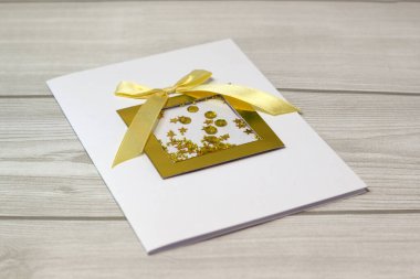 Güzel beyaz ve altın el yapımı, saten kurdeleli Noel kartı.