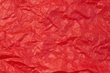 Crumpled paper background made from a blood red sheet of wrapping paper top view clipart
