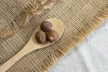Nutmeg makrosu ahşap kaşıkla sert keten desenli arka plan görünümünde.
