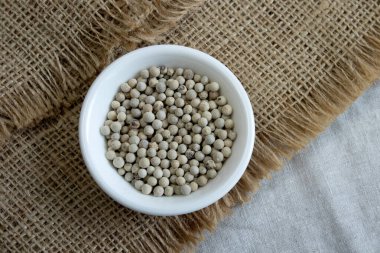 Baharatlar, beyaz biberler, keten üzerine serpiştirilmiş biber tohumları, yakın çekim üst görüş dar odak çizgisi, sığ alan derinliği