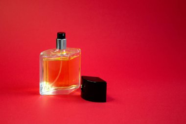 Parfüm şişesi parlak kırmızı arka plan görünümünde.