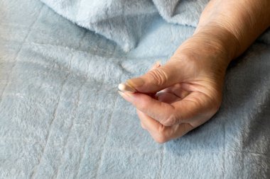 Hap tutan yaşlı bir kadının elleri. Elleri bağlı yaşlı bir kadın. Kapatın ve açık mavi bir battaniye getirin.