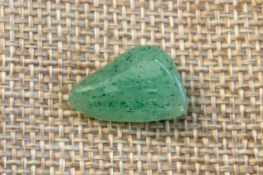 Doğal mineral kaya numunesinin makroskopi - bej arka plan görünümünde yuvarlanan yeşil bulvar taşı