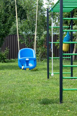 Mavi plastik salıncak yeşil güneşli bahçede, ön manzara