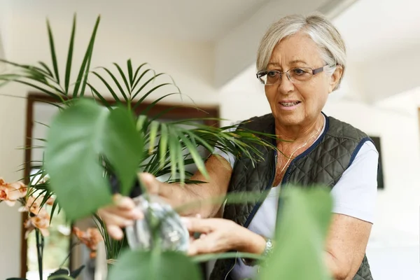 自宅で鉢植えの世話をする幸せな先輩女性 — ストック写真