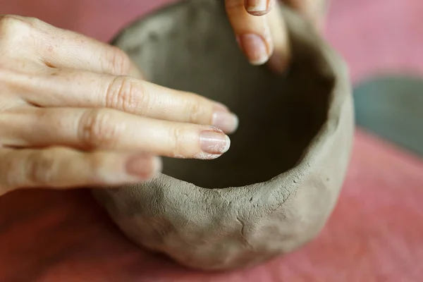 Women\'s hands knead the clay and sculpt a cup from it. The process of manufacturing a ceramic product,close up.
