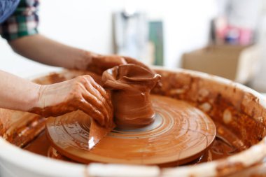 Unrecognisable female sculptor while she making clay pot on pottery wheel. Idea of small business and entrepreneurship. Home hobby, entertainment and leisure. Art studio.