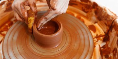 Master making a pot on pottery wheel, top view.