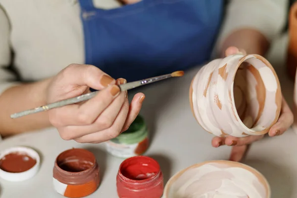 Woman hands, pottery studio and painting cup in workshop for sculpture, creative manufacturing or design. Painter, ceramics product and brush process, artistic pattern or production in small business.
