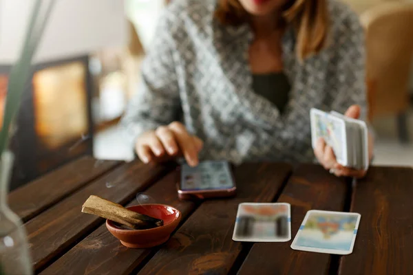 stock image Fortune teller with tarot cards on table near burning candle.Tarot cards spread on table with magic herbs and palo santo aroma sticks. Forecasting concept