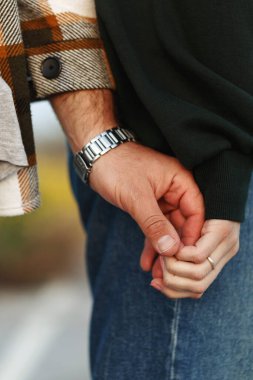 Güzel günbatımında sahada iki eli birbirine değdirin. Günlük kıyafetler. Erkek eli saat takar, kadın eli yüzük takar .
