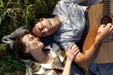 Parkta piknikte romantik bir randevuda aşık mutlu çift. Gitarla çalmak ve dışarıda eğlenmek. Üst görünüm.