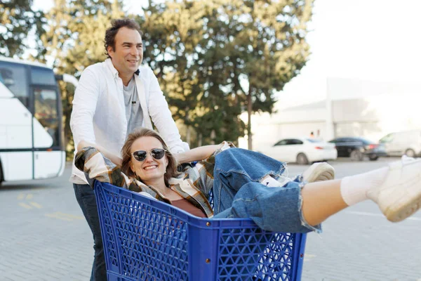 Mulher Feliz Sentado Dentro Carrinho Compras Homem Empurrando Carrinho Compras — Fotografia de Stock