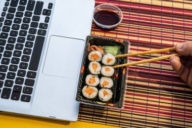 Laptopun yanında soya soslu suşi, Asya yemekleri.