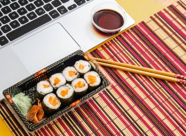 Laptopun yanında soya soslu suşi, Asya yemekleri.