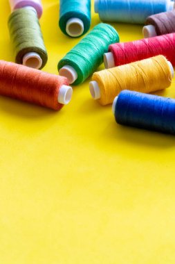 Çeşitli renklerin dikimi için iplik maketleri, metin için alanı olan sarı bir arkaplan üzerinde.