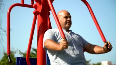 Biyolojik sağlık parkındaki makinede spor yapan bir adam.