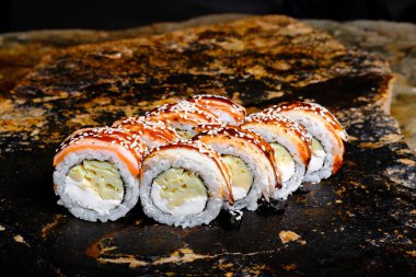 This appetizing photo showcases a sushi roll that is sure to make your mouth water. The roll is expertly crafted and features fresh ingredients, including rice, seaweed, and a variety of tasty