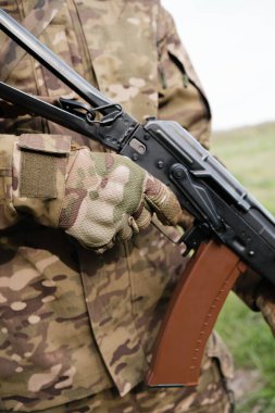 Silahlı bir adam AK-47 'yi yakın planda tutuyor.