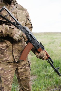 Silahlı bir adam AK-47 'yi yakın planda tutuyor.