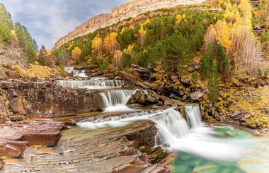 The magic of the autumn landscape of Monte Perdido, the Las Gradas de Soaso Waterfall is located in the Valley of the Arazas River, in the Ordesa y Monte Perdido National Park. clipart