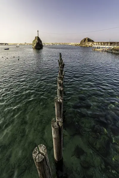 Asturias 'ın güzel Cudillero kasabasının marinasında deniz tabanına saplanmış eski tahta direkler.