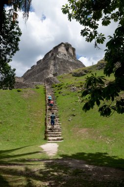 San Ignacio, Belize - 24 Ağustos 2019: Ziyaretçiler Xunantunich arkeoloji sahasındaki 'El Castillo' harabelerini güneşli Maya 'ya doğru dik merdivenlerden çıkıyorlar