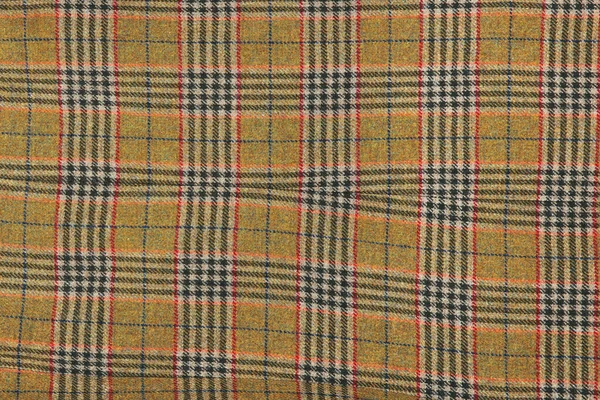 Wool plaid texture. Soft and warm folded alpaca wool blanket. Green and orange wool plaid texture macro shot. Wool coat
