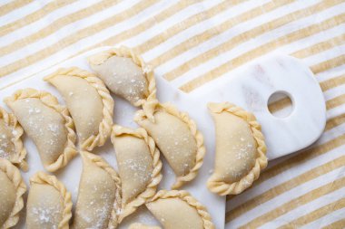 Mermer bir tahtanın üzerinde hazırlanmış taze ev yapımı hamur tatlısı. Geleneksel el işçiliği sergileniyor. Lezzetli malzemelerle dolu çiğ hamur, pişirmeye hazır..