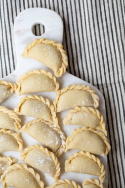 Mermer bir tahtanın üzerinde hazırlanmış taze ev yapımı hamur tatlısı. Geleneksel el işçiliği sergileniyor. Lezzetli malzemelerle dolu çiğ hamur, pişirmeye hazır..