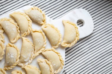 Mermer bir tahtanın üzerinde hazırlanmış taze ev yapımı hamur tatlısı. Geleneksel el işçiliği sergileniyor. Lezzetli malzemelerle dolu çiğ hamur, pişirmeye hazır..