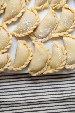Mermer bir tahtanın üzerinde hazırlanmış taze ev yapımı hamur tatlısı. Geleneksel el işçiliği sergileniyor. Lezzetli malzemelerle dolu çiğ hamur, pişirmeye hazır..
