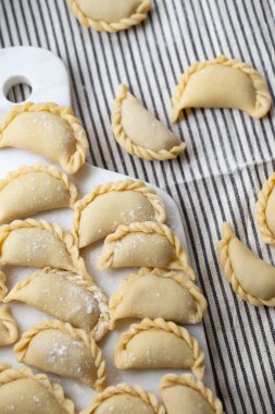 Mermer bir tahtanın üzerinde hazırlanmış taze ev yapımı hamur tatlısı. Geleneksel el işçiliği sergileniyor. Lezzetli malzemelerle dolu çiğ hamur, pişirmeye hazır..