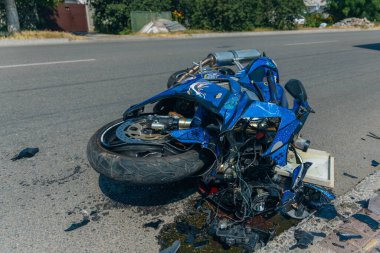 Motosiklet bir trafik kazasından sonra kaldırımda yatıyor. Hasarlı motosiklet asfalt yolda duruyordu. Ciddi bir kaza. DNIPRO, UKRAINE 6 Temmuz 2020