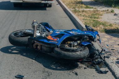 Motosiklet bir trafik kazasından sonra kaldırımda yatıyor. Hasarlı motosiklet asfalt yolda duruyordu. Ciddi bir kaza. DNIPRO, UKRAINE 6 Temmuz 2020