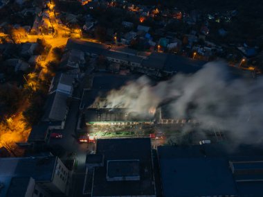 Yanan bir endüstriyel binanın havadan görüntüsü. Gece yangını. Duman gökyüzünde Depoda güçlü ateş.