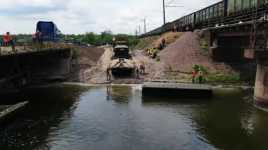 Ukrayna ordusunun Pontoon köprüsü. Yok edilen köprünün yakınına geçici bir geçit kurulmuş. Askerler duba feribotu topluyor. Bir İHA 'dan üst görünüm. 