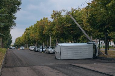 Araba bir sokak lambasına çarptı ve yan yattı. Araba bir tarafta kaldı. Yoldaki kırık ön cam trafik kazaları. DNIPRO, UKRAINE - 12 Ağustos 2023
